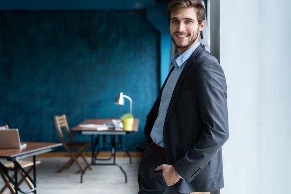 Confident professional handsome businessman standing near window in his office — Stock Photo, Image