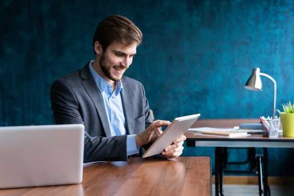 Hombre sonriente en la oficina trabajando en la tableta digital . — Foto de Stock