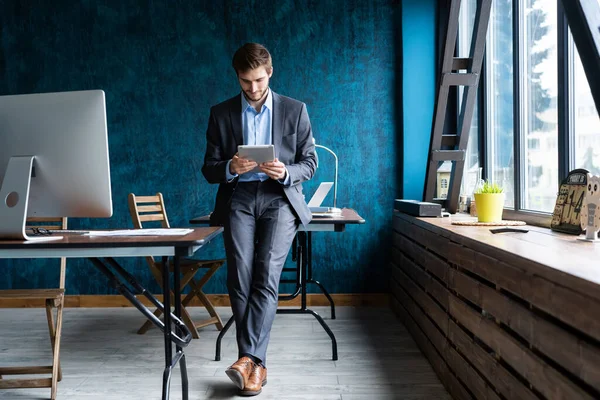 Knappe, elegante zakenman die aan een tablet werkt. — Stockfoto