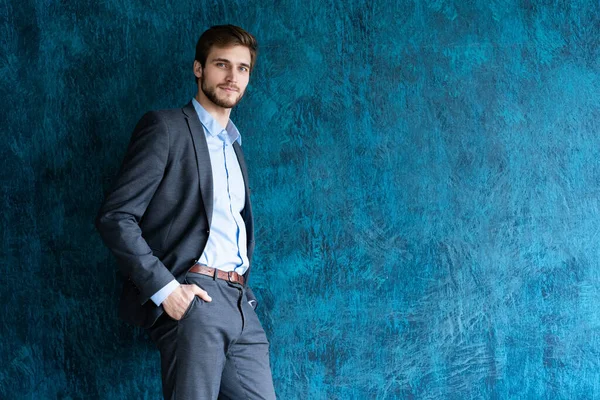 Retrato de jovem bonito em pé contra a parede azul com espaço de cópia . — Fotografia de Stock