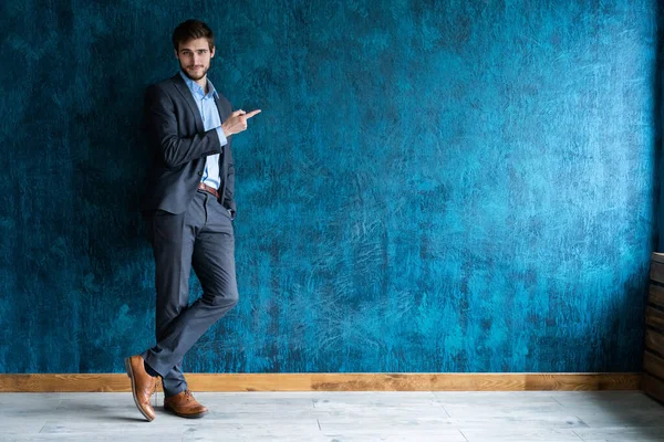Full length portrait of young handsome businessman with smile pointing with finger. — Stock Photo, Image