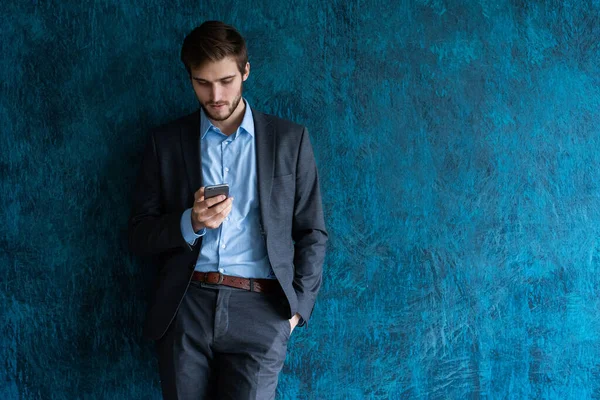 Beau jeune homme d'affaires barbu au bureau en utilisant un téléphone portable à l'intérieur. — Photo