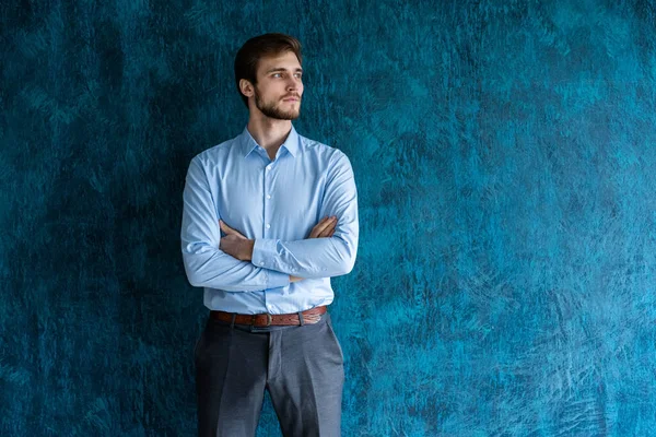 Ritratto di bel giovane in piedi contro il muro blu con spazio copia. — Foto Stock