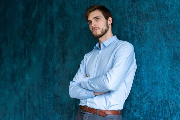 Portrét pohledného mladého muže stojícího proti modré stěně s kopírovacím prostorem. — Stock fotografie
