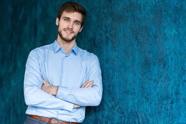 Retrato de jovem bonito em pé contra a parede azul com espaço de cópia . — Fotografia de Stock