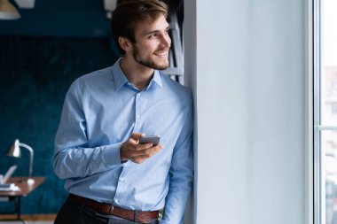 Ofiste cep telefonu kullanan yakışıklı, sakallı bir iş adamı..