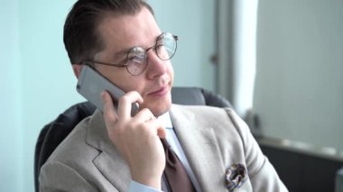 Ofiste telefonla konuşan yakışıklı bir adam. İş adamı akıllı telefondan konuşuyor. Mutlu adam telefonu arıyor..
