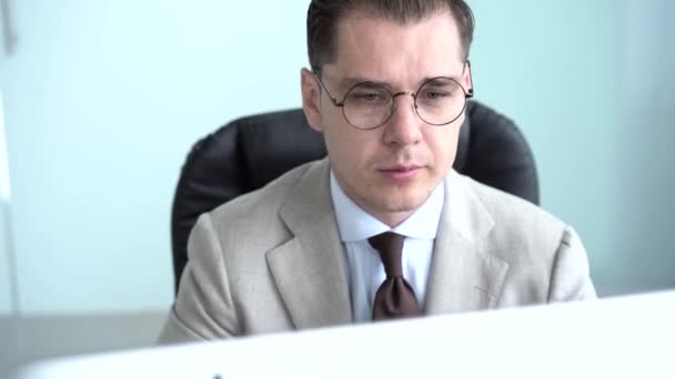 Casual businessman working in office, sitting at desk, typing on keyboard, looking at computer screen — Stock Video