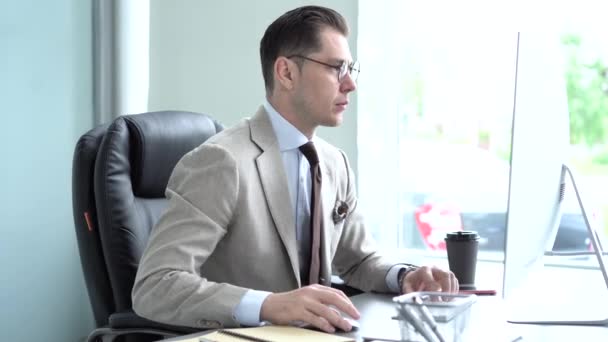 Casual zakenman werkt in het kantoor, zit aan het bureau, typen op het toetsenbord, kijken naar computerscherm — Stockvideo