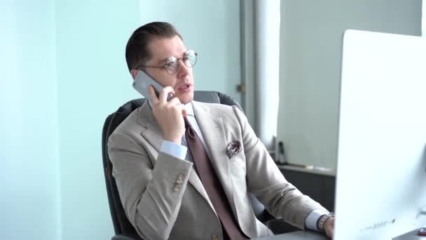 Un hombre guapo hablando por teléfono en la oficina. Hombre de negocios hablando por teléfono inteligente. Hombre feliz llama al teléfono . — Vídeo de stock