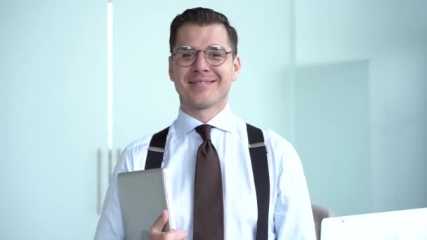 オフィスでカメラを見てメガネを身に着けている幸せなビジネスマンを自信を持って,正の男性従業員エグゼクティブ笑顔顔は現代的なオフィスでポーズをとって良い仕事のキャリアに満足. — ストック動画