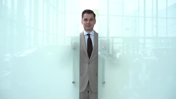 Возбужденный молодой человек открывает дверь в современный офис — стоковое видео