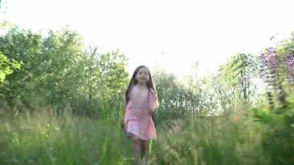 Gadis kecil yang cantik berjalan di lapangan pinus bluebonnets dan memetik bunga. — Stok Video