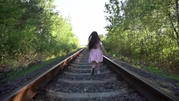 Linda menina andando na estrada de ferro na floresta no dia de verão . — Vídeo de Stock