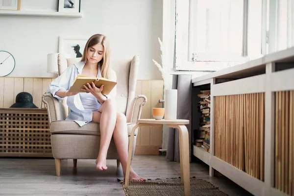Όμορφο κορίτσι διαβάζει ένα βιβλίο στο σπίτι. Ψυχαγωγία εσωτερικών χώρων — Φωτογραφία Αρχείου