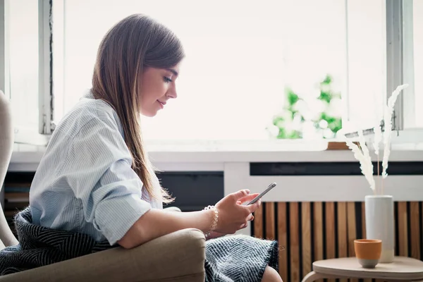 自宅で彼女の携帯電話を使用して美しい若い女性の肖像画 — ストック写真