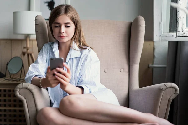 Retrato de una hermosa joven usando su teléfono móvil en casa — Foto de Stock