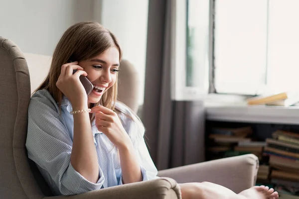 Νεαρή χαρούμενη γυναίκα που μιλάει στο κινητό τηλέφωνο στο σπίτι. — Φωτογραφία Αρχείου