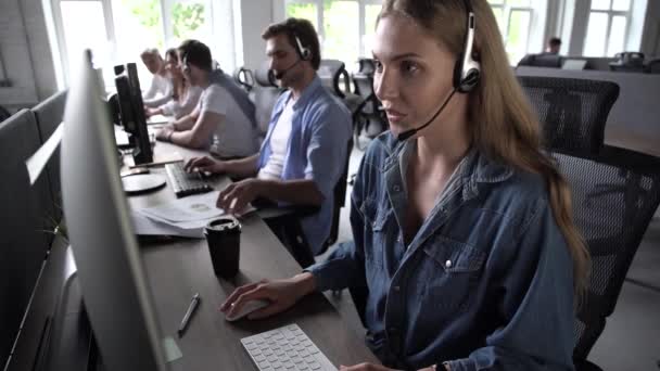 Жінка-агент в гарнітурі використовує відповіді на вхідні дзвінки ПК, спілкуючись з клієнтом, надає професійну підтримку клієнтам — стокове відео