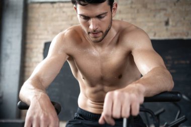 Spor salonunda egzersiz bisikleti kullanan bir adam. Spor salonunda spor yapan erkek, kardiyo çalışması için hava bisikleti kullanıyor.