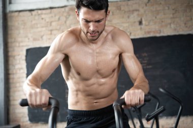 Spor salonunda egzersiz bisikleti kullanan bir adam. Spor salonunda spor yapan erkek, kardiyo çalışması için hava bisikleti kullanıyor.