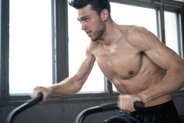 Spor salonunda egzersiz bisikleti kullanan bir adam. Spor salonunda spor yapan erkek, kardiyo çalışması için hava bisikleti kullanıyor.