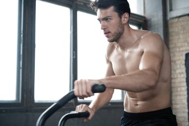 Spor salonunda egzersiz bisikleti kullanan bir adam. Spor salonunda spor yapan erkek, kardiyo çalışması için hava bisikleti kullanıyor.