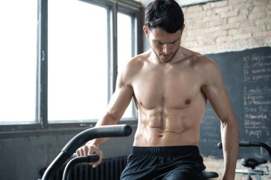 Spor salonunda egzersiz bisikleti kullanan bir adam. Spor salonunda spor yapan erkek, kardiyo çalışması için hava bisikleti kullanıyor.