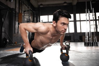 Yakışıklı, kaslı bir adam halter egzersizinde halterle şınav çekiyor..