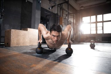 Yakışıklı, kaslı bir adam halter egzersizinde halterle şınav çekiyor..