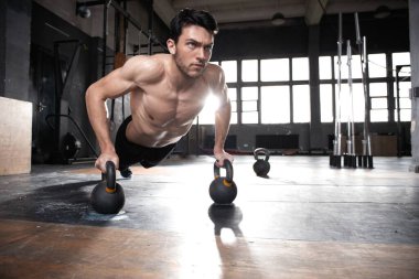 Yakışıklı, kaslı bir adam halter egzersizinde halterle şınav çekiyor..