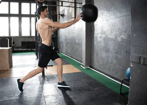 Young strong fit muscular man doing throwing medicine ball up on the wall for crossfit training hard core workout in gym — Stock Photo, Image