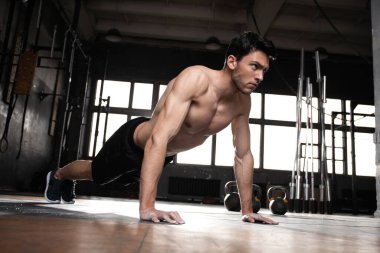 Spor salonunda şınav çeken kaslı bir adam..