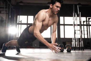 Spor salonunda şınav çeken kaslı bir adam..