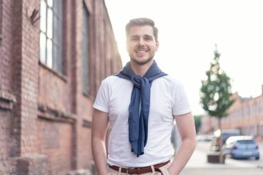 Şehirde yürüyüş yapan yakışıklı bir genç adam. Neşeli genç adam şehri geziyor..