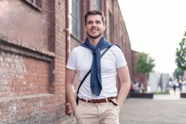 Şehirde yürüyüş yapan yakışıklı bir genç adam. Neşeli genç adam şehri geziyor..