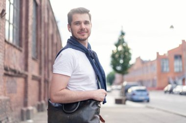 Şehirde yürüyüş yapan yakışıklı bir genç adam. Neşeli genç adam şehri geziyor..