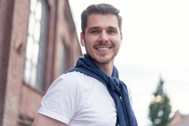 Şehirde yürüyüş yapan yakışıklı bir genç adam. Neşeli genç adam şehri geziyor..