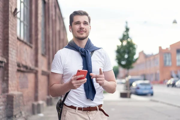 街を歩きながら音楽を聴いているハンサムな笑顔の男 — ストック写真