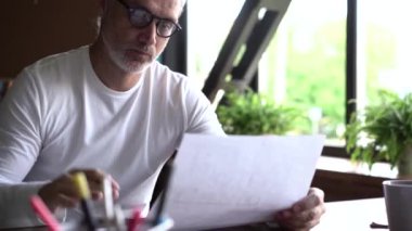 Ofiste çizimlerle çalışan olgun beyaz bir mimar. Profesyonel adam yeni bina geliştirme projesi üzerinde çalışıyor