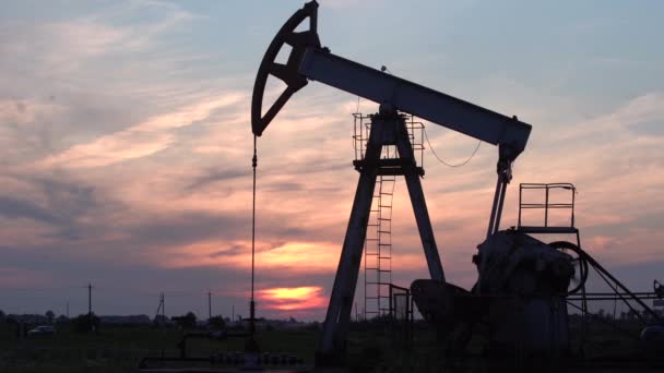 Silueta pracovního olejového čerpadla z ropného pole při západu slunce. — Stock video