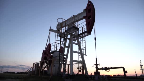 Silhouet van werkende oliepomp van olieveld bij zonsondergang. — Stockvideo