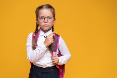 Okul çantalı küçük kız parmağını kaldırıyor..