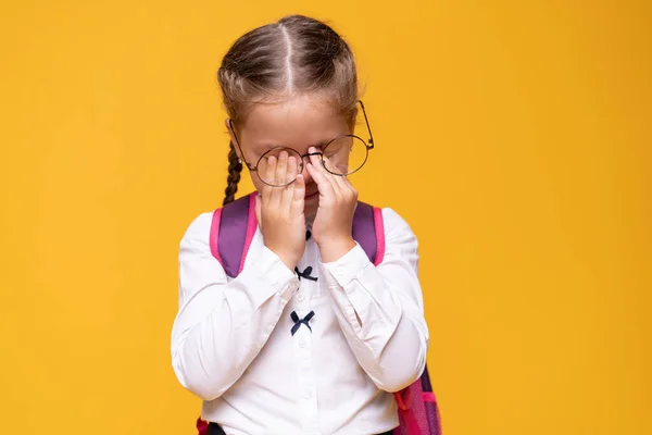 Portret triest klein meisje staan op een gele achtergrond — Stockfoto