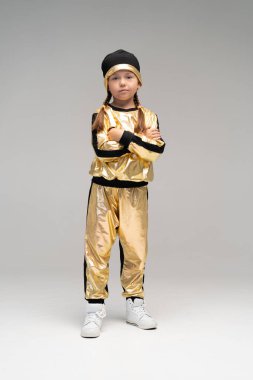 Beyaz arka planda yalnız dans eden altın takım elbiseli mutlu küçük kız..