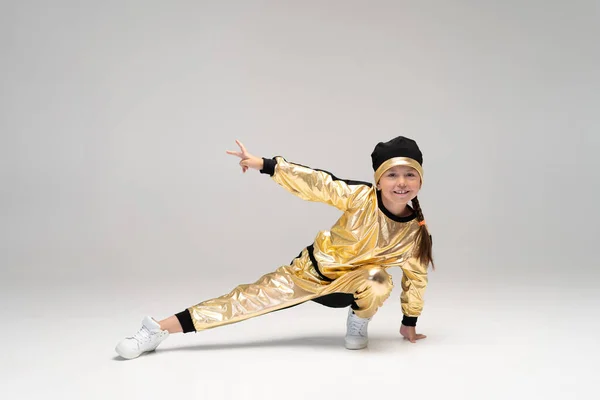 Happy little girl in gold suit dancing isolated on white background. — Stock Photo, Image