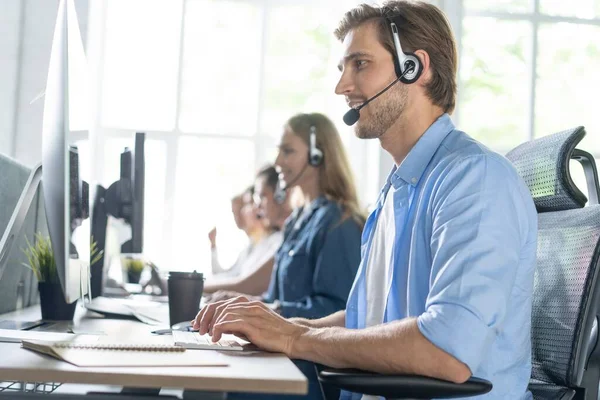 Jonge knappe mannelijke customer support telefoon operator met headset werken in call center — Stockfoto