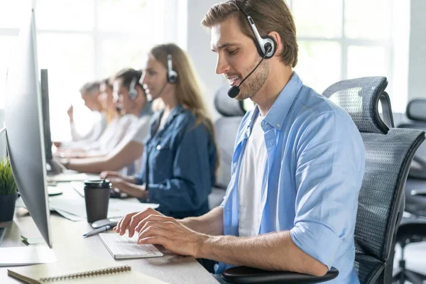 Ung stilig manlig kundsupport telefonoperatör med headset arbetar i callcenter — Stockfoto