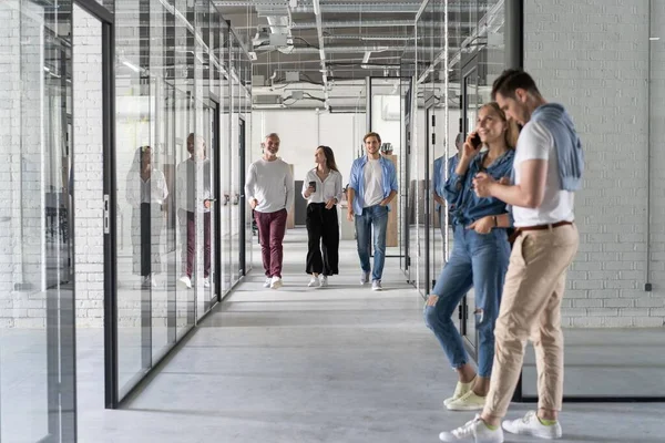 Longitud completa de los jóvenes modernos en ropa casual inteligente tener una discusión mientras camina a través de la oficina — Foto de Stock