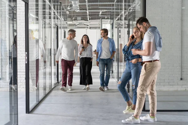 Longitud completa de los jóvenes modernos en ropa casual inteligente tener una discusión mientras camina a través de la oficina — Foto de Stock